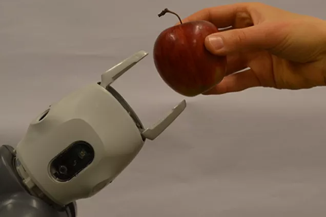 photo. human hand handing an apple to a robot hand. 