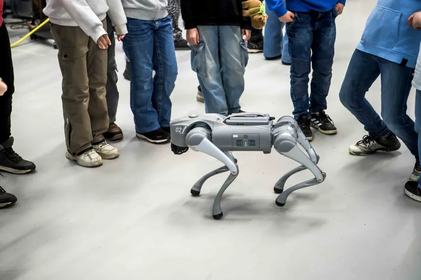 Skolbarn tittar på en fyrbent robot.